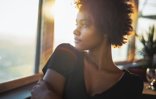 Black Woman – Trauma Therapy for Women via Telehealth in Seattle, WA Black woman reflecting in sunlight through a window, symbolizing healing from trauma via Telehealth in Seattle, WA