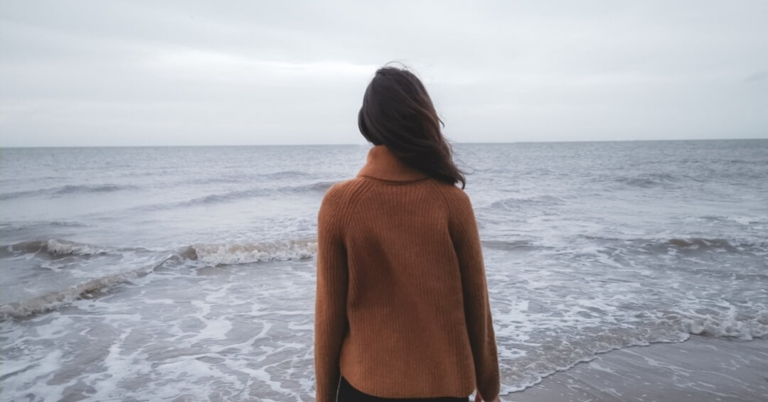 Backview of Woman with long hair facing ocean