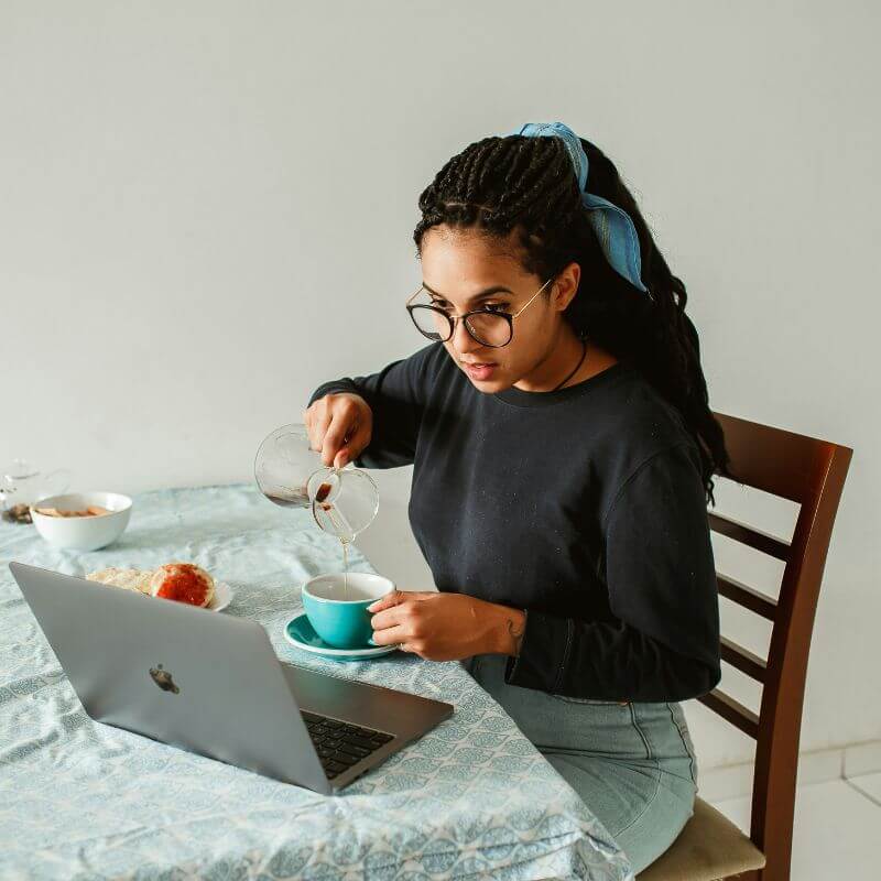 Online therapy session for women in Seattle from the comfort of home Woman preparing tea while attending an online therapy session from home on her laptop