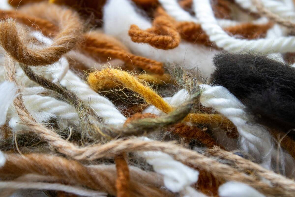An abstract close‑up of intertwined yarn in soft, earthy tones. The image symbolizes the mental load mothers carry — the emotional, logistical, and invisible threads woven together every day.